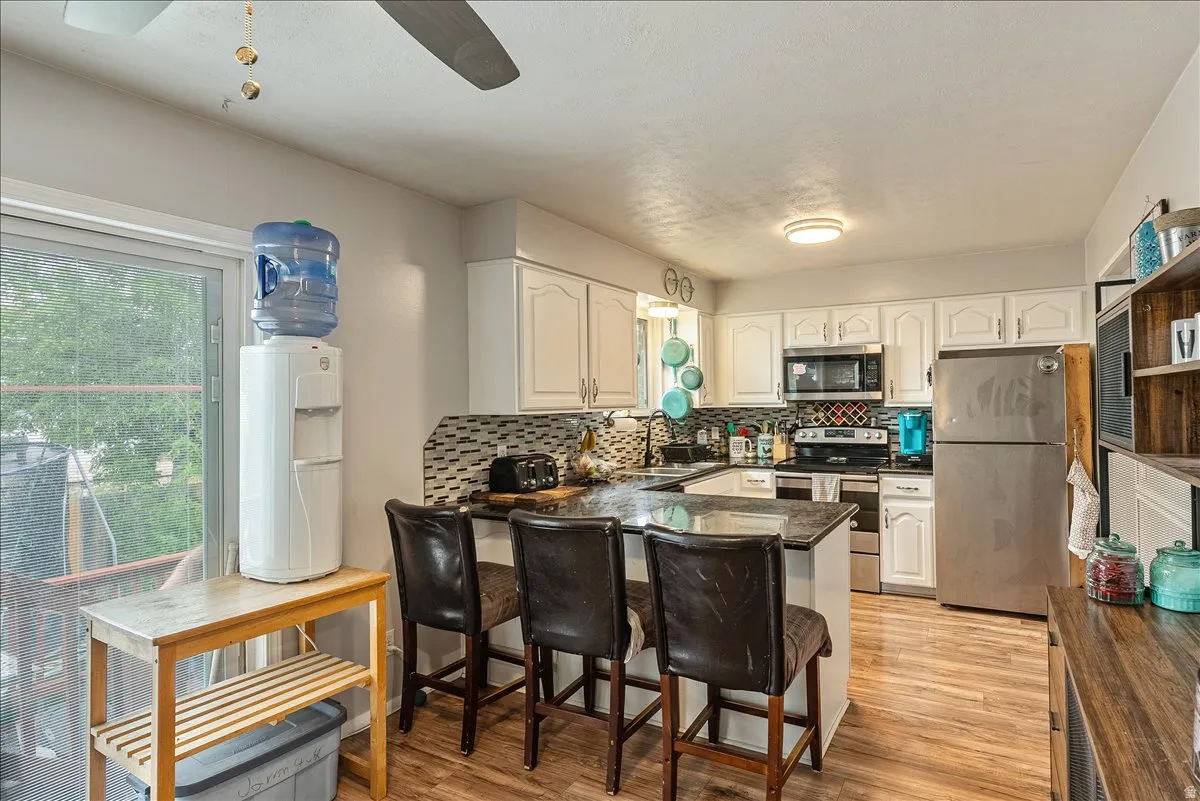Modern kitchen featuring white cabinetry, stainless steel appliances, and wood-finish flooring