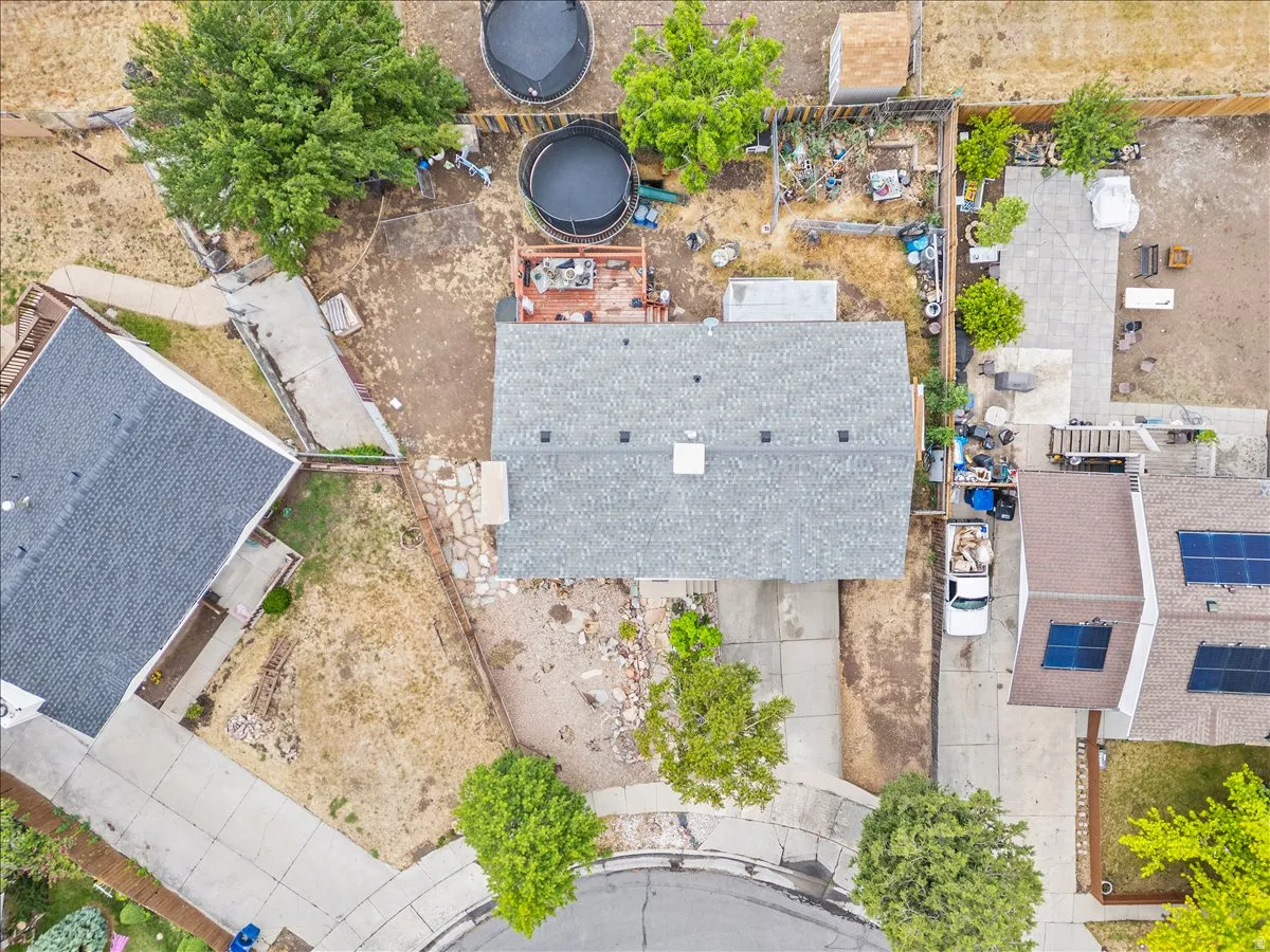 Residential property with a gray shingle roof, a paved driveway, and an expansive backyard area