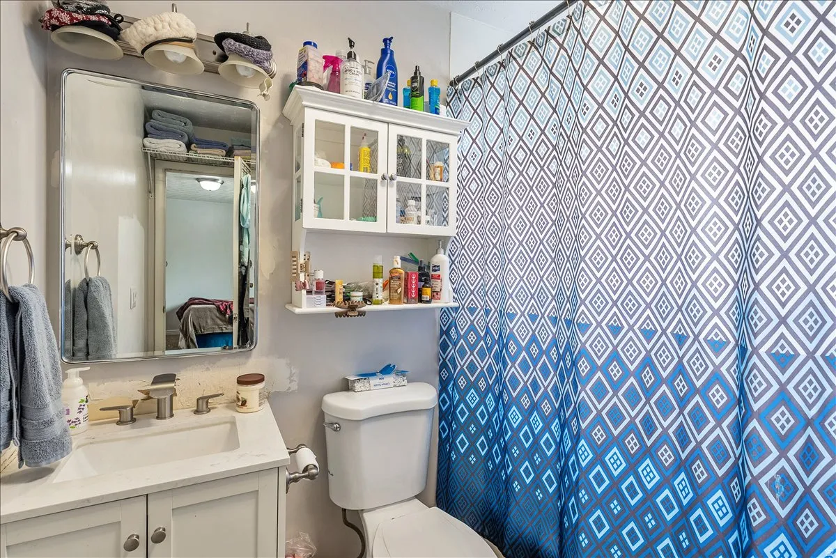 Bathroom featuring a white vanity with an integrated sink, polished chrome faucet, and rectangular mirror with overhead lighting