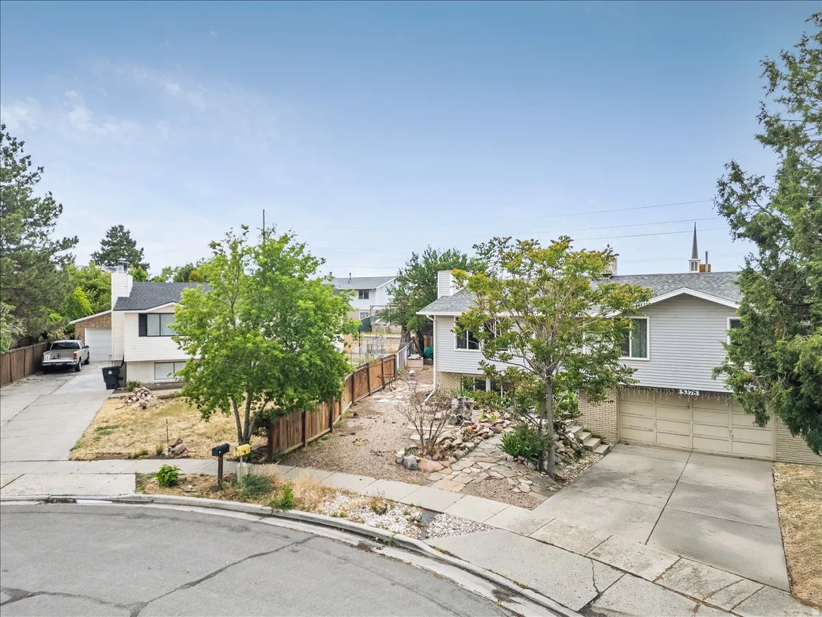 Split-level residence featuring a light gray exterior and a concrete driveway