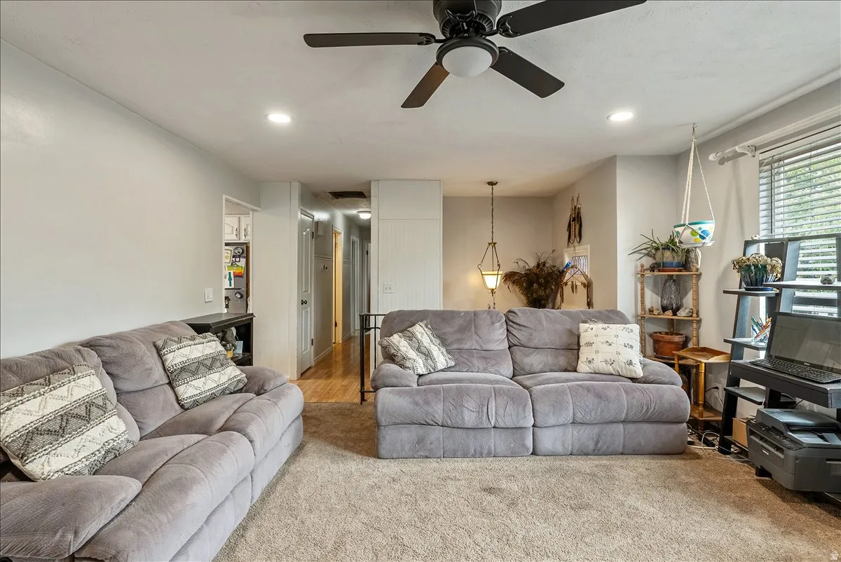Spacious living area featuring neutral carpeting, recessed lighting, and a ceiling fan