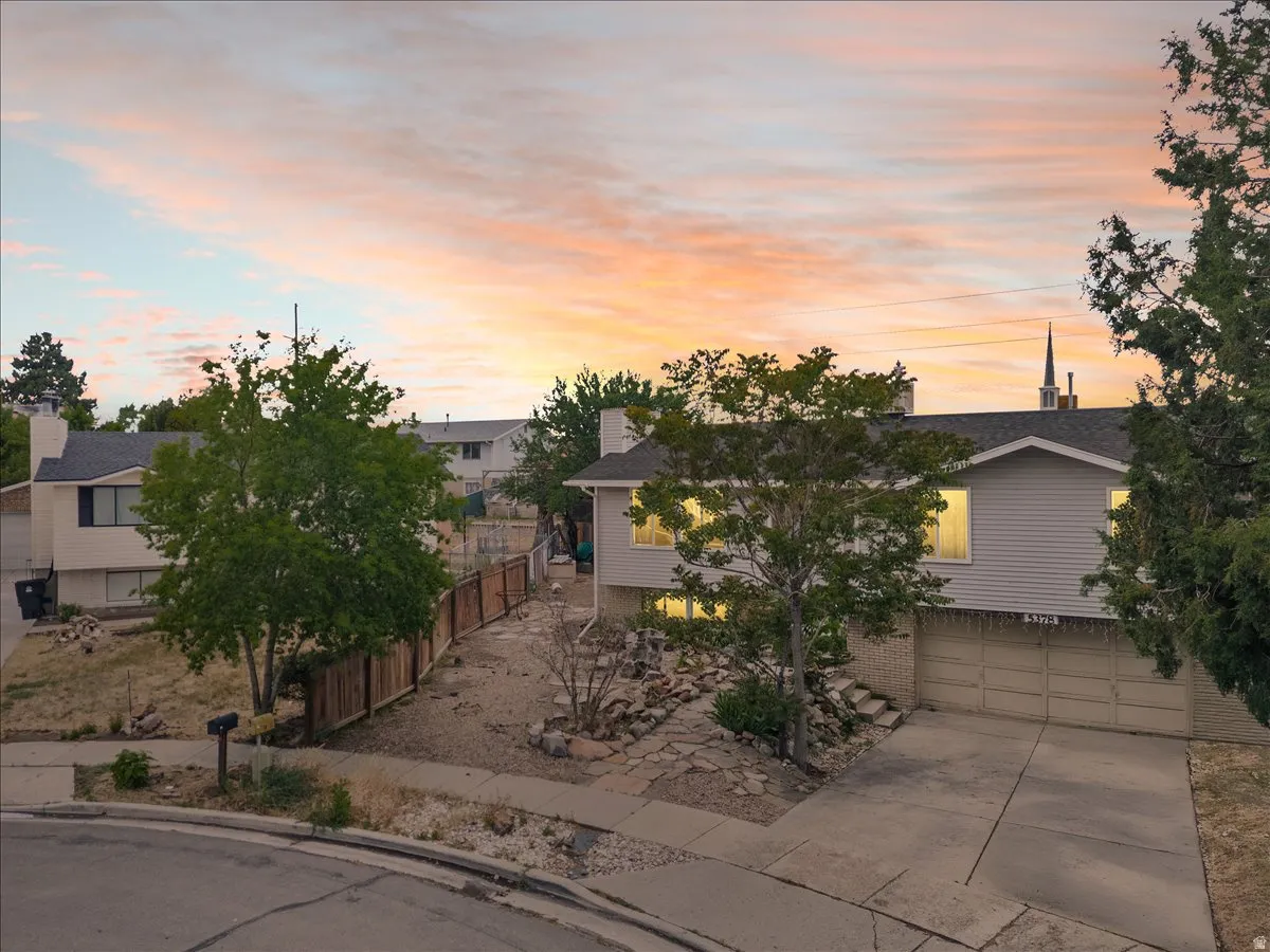 Split-level residence featuring a two-car garage, concrete driveway, and established front yard trees
