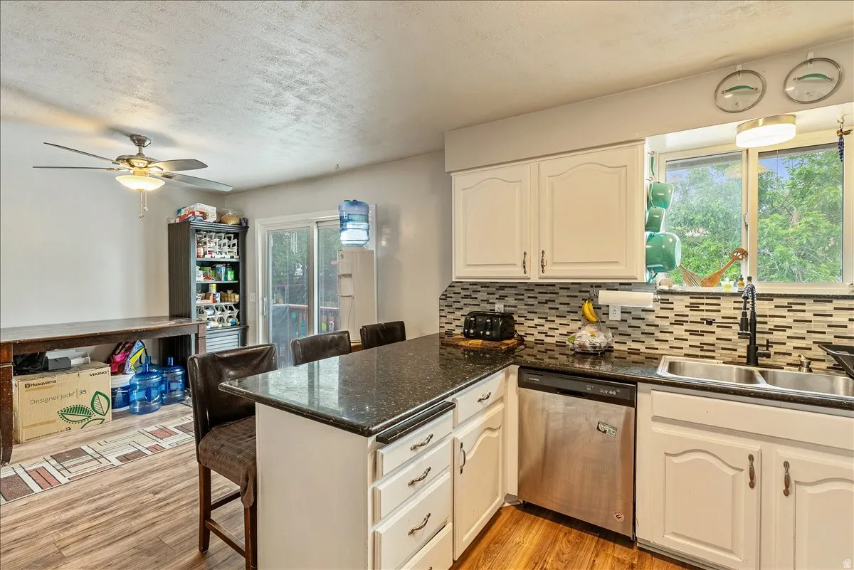 Kitchen featuring white cabinetry, dark speckled countertops, and a mosaic tile backsplash