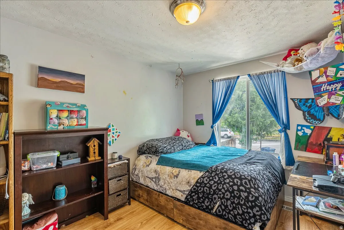 Room featuring wood-finish flooring, a contemporary ceiling light fixture, and large windows with blue drapery