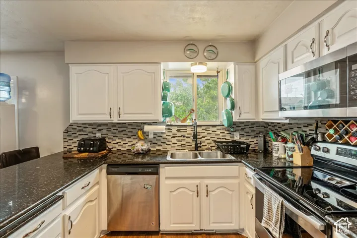 Kitchen featuring white cabinetry, dark speckled countertops, and a mosaic tile backsplash
