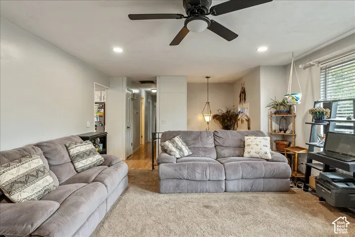 Spacious living area featuring neutral carpeting, recessed lighting, and a ceiling fan