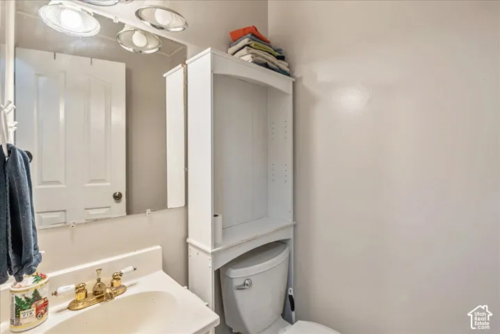 Bathroom featuring a white vanity with an integrated sink, polished brass-finish faucet, and a wall-mounted mirror with overhead lighting