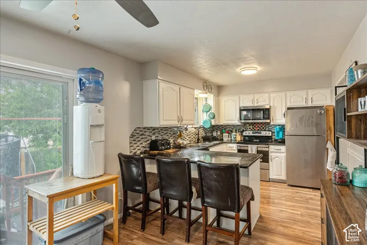 Modern kitchen featuring white cabinetry, stainless steel appliances, and wood-finish flooring
