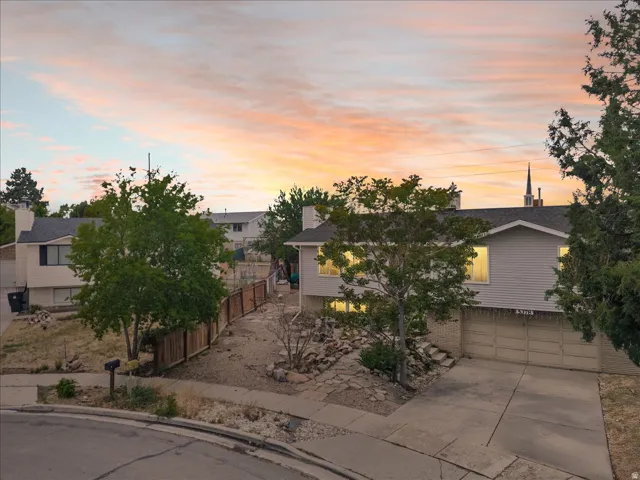 Split-level residence featuring a two-car garage, concrete driveway, and established front yard trees