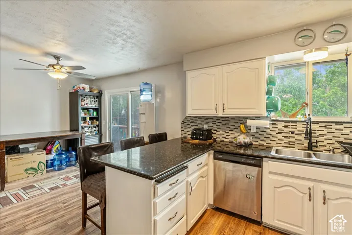 Kitchen featuring white cabinetry, dark speckled countertops, and a mosaic tile backsplash