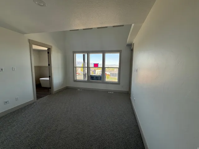 Carpeted interior space with neutral wall tones and a distinct ceiling line