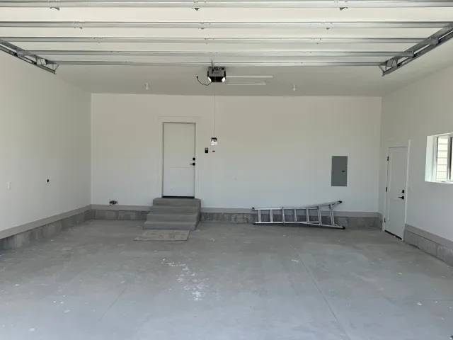 Spacious garage featuring a concrete floor, painted walls, and built-in overhead garage door track system