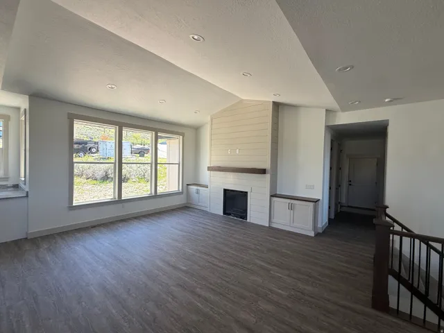 Spacious living area featuring wood-finish flooring and a vaulted ceiling with recessed lighting