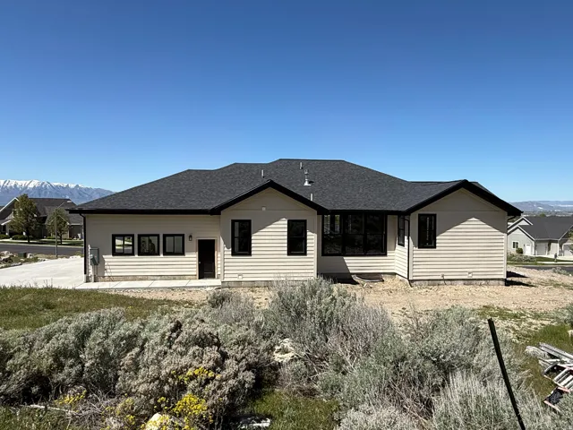 Contemporary ranch-style residence featuring horizontal siding, a dark shingle roof, and contrasting black-framed windows