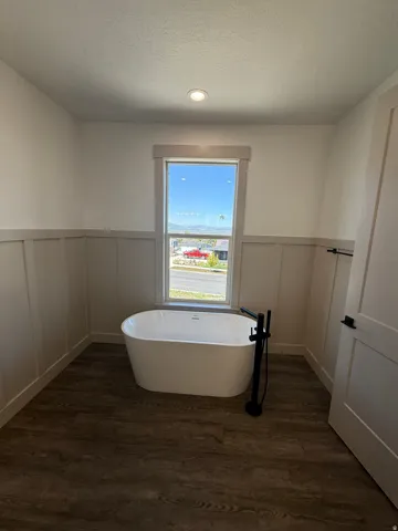 Freestanding soaking tub with a matte black floor-mounted faucet, set against a board and batten wall treatment