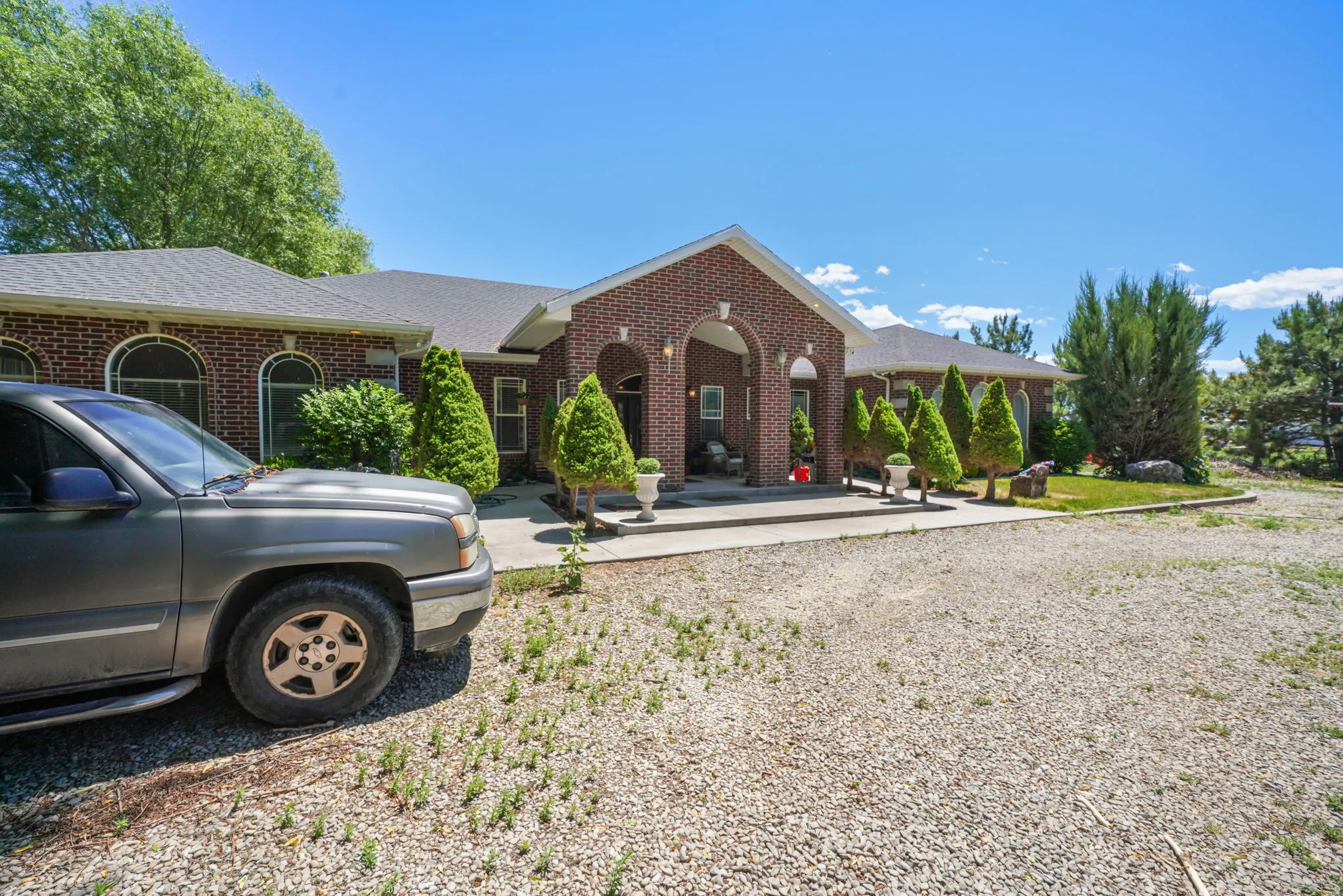 Full brick exterior with arched entryways, featuring a covered porch and a paved walkway.  Concrete ramp on left side.