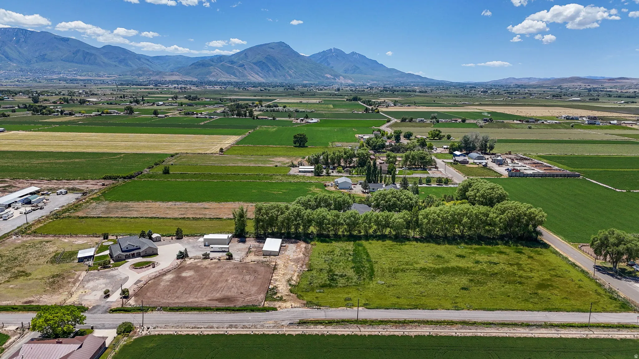 Expansive rural property featuring multiple outbuildings, agricultural fields, and distant mountain ranges