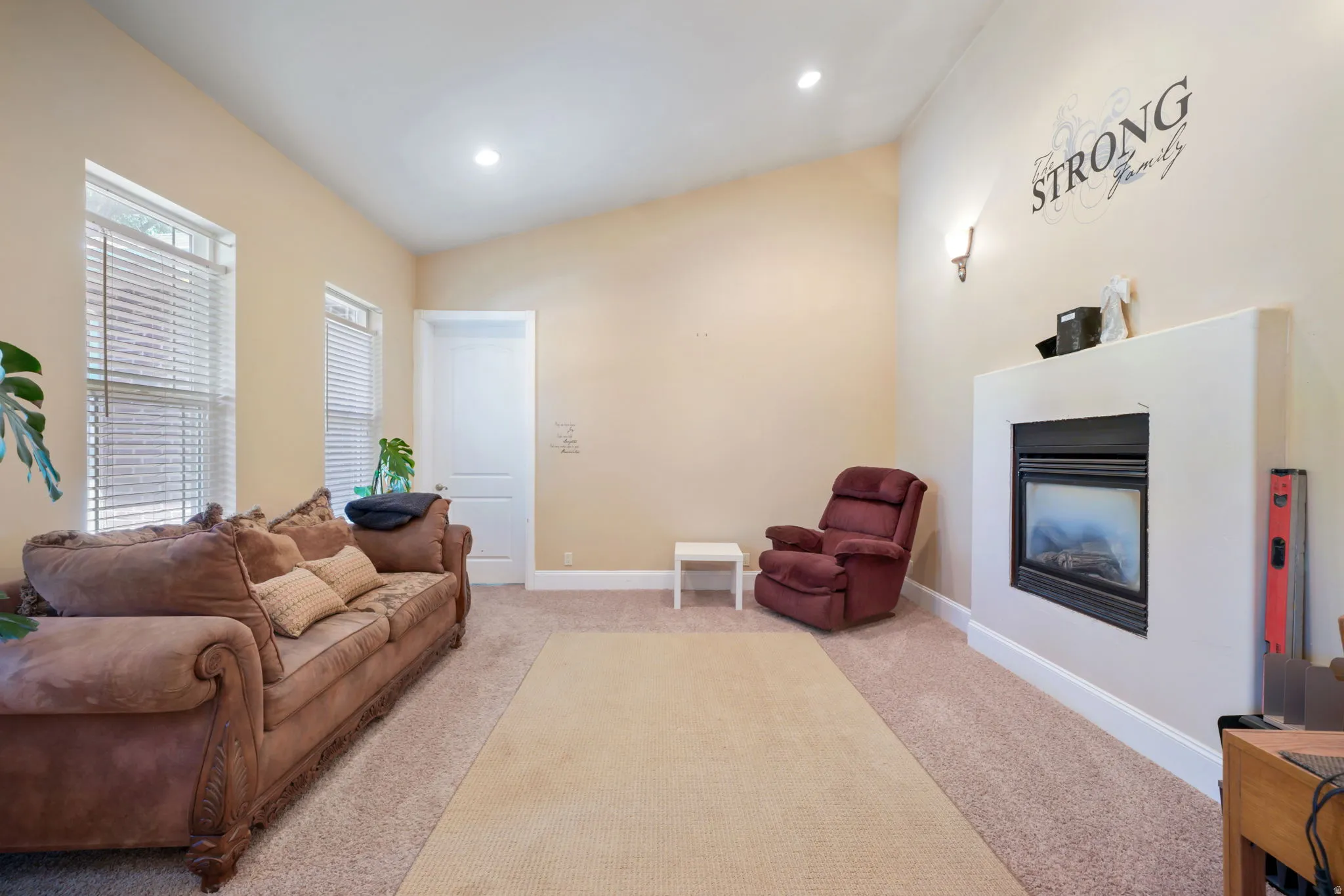 Living left of entrance with a see-through fireplace, vaulted ceilings and recessed lighting.