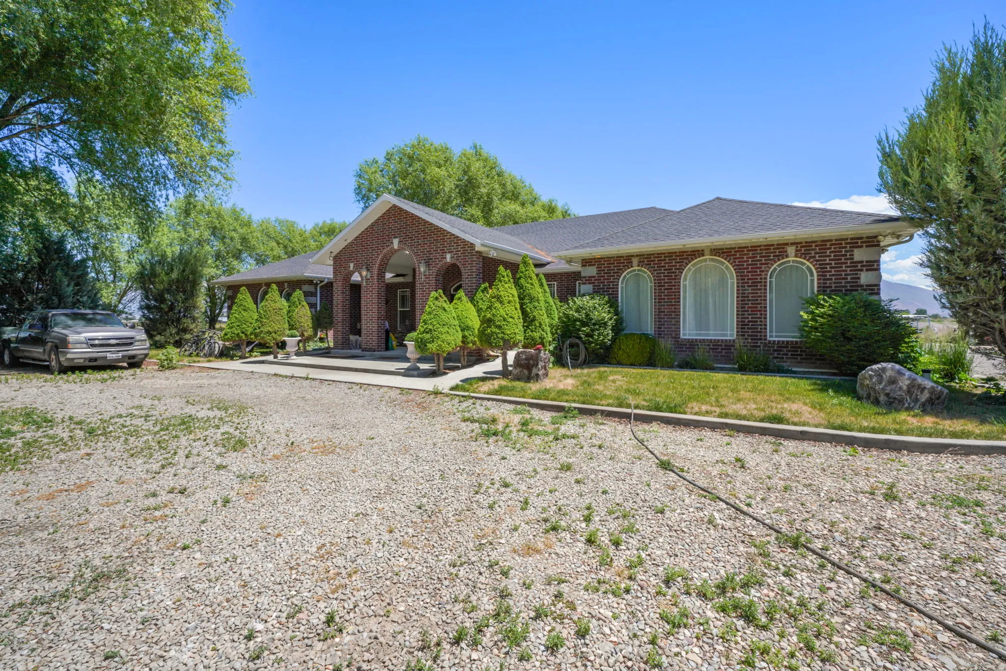 Full brick exterior featuring a covered entry porch, arched windows, and a dark shingle roof