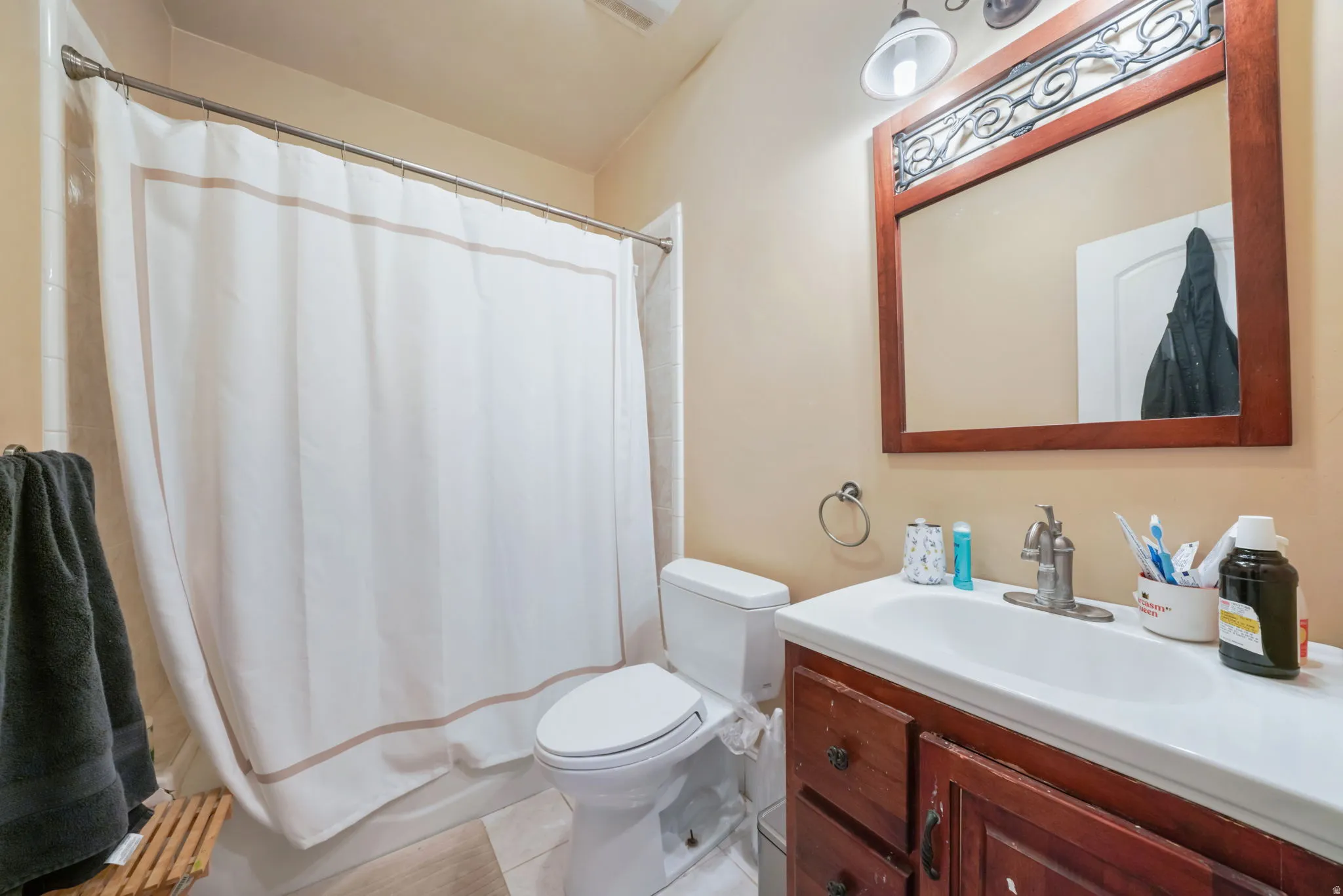 Second primary bathroom featuring a vanity with dark wood-finish cabinetry, a white countertop with an integrated sink, and a framed mirror with decorative metalwork