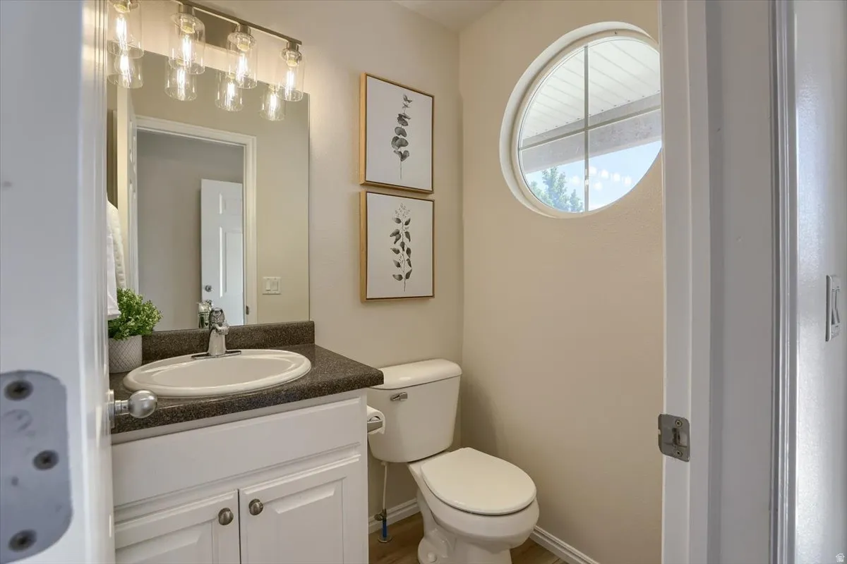 Bathroom featuring a white vanity with built-in sink, dark countertop, and a round window