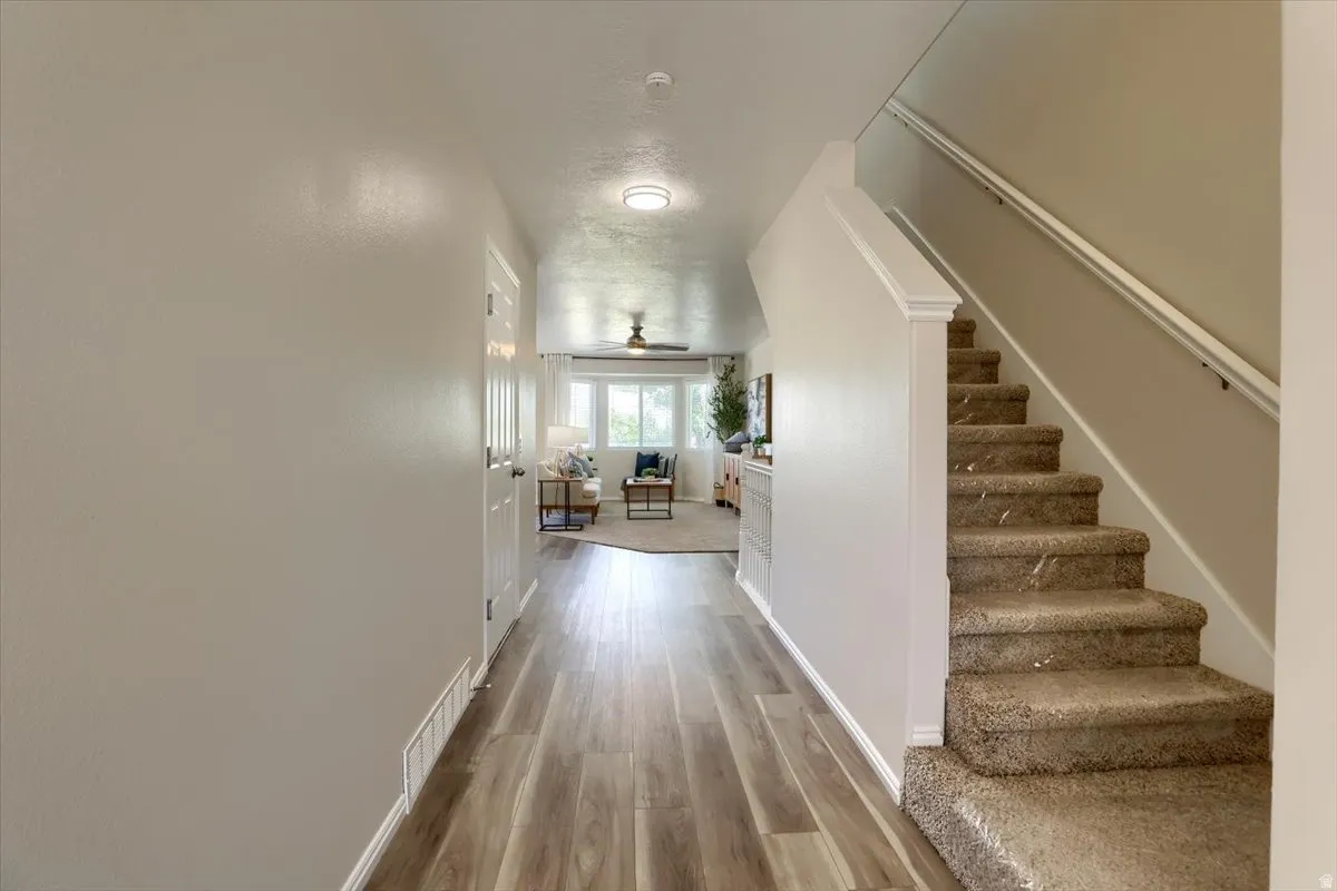Entryway featuring wood-finish flooring, light neutral paint, a carpeted staircase with white trim, and a white interior door