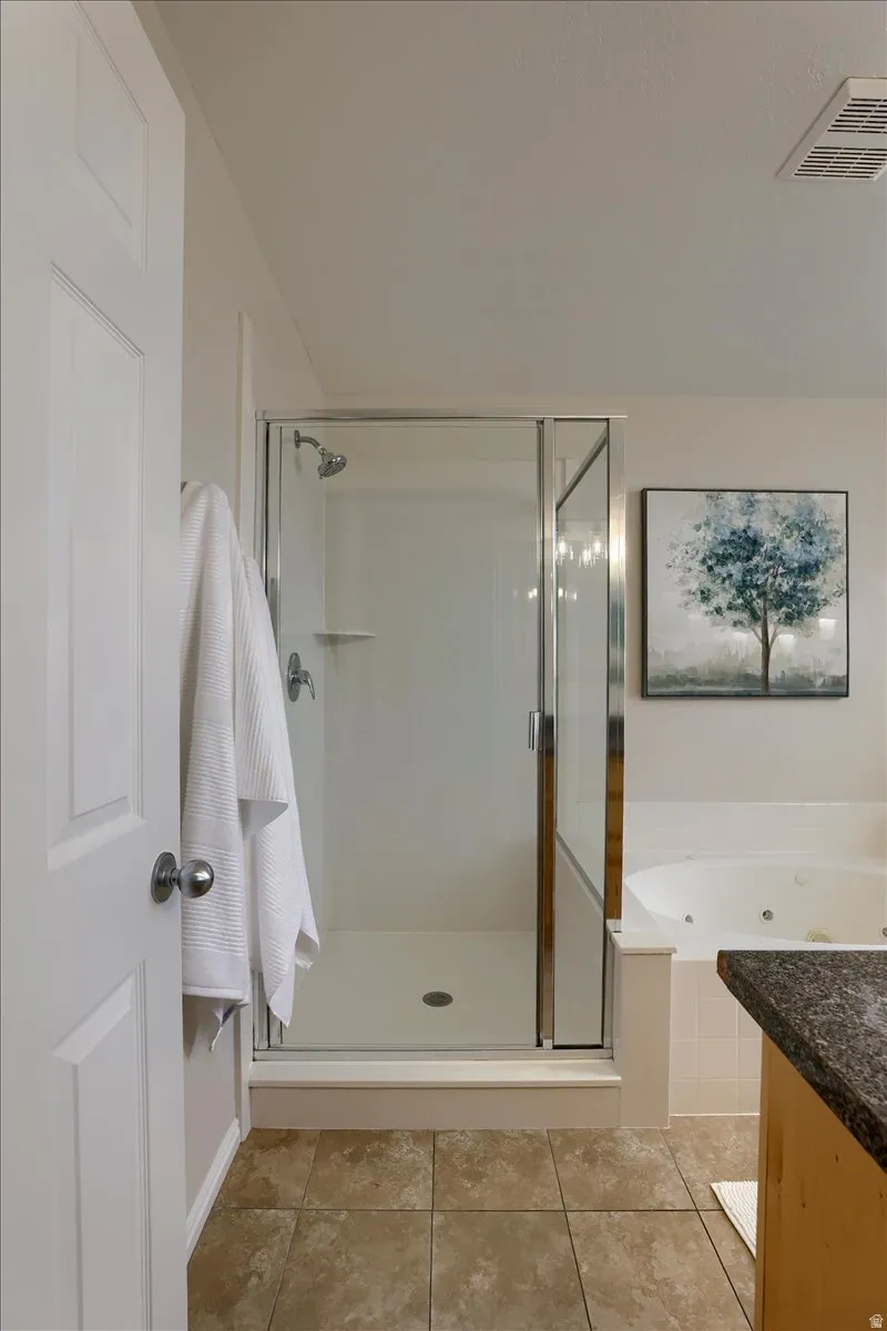 Glass-enclosed shower with a built-in shelf, adjacent to a jetted soaking tub