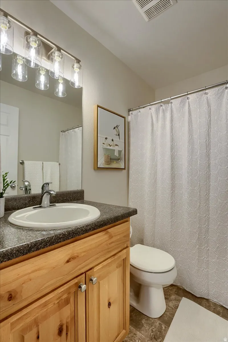 Bathroom featuring a wood-finish vanity with a built-in sink, a speckled countertop, and a chrome faucet
