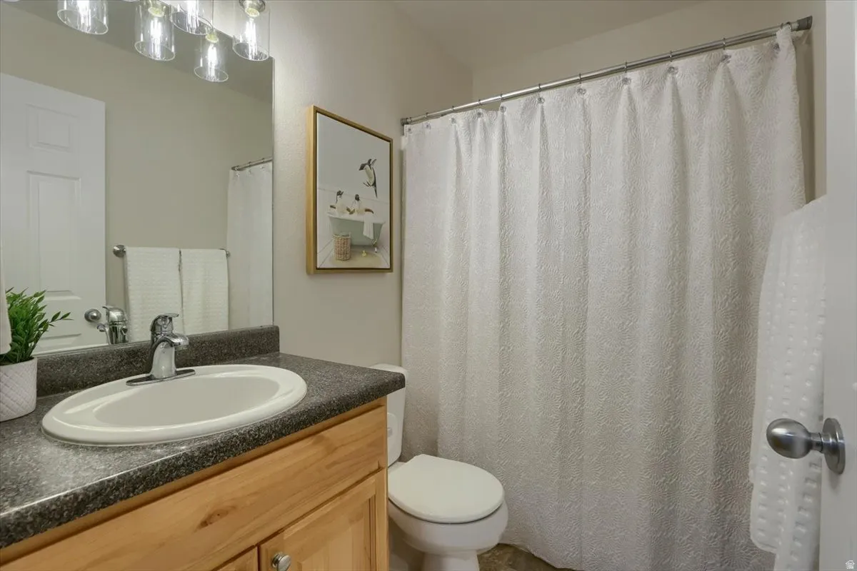 Bathroom featuring a wood-finish vanity with an integrated sink, dark countertop, and brushed nickel fixtures