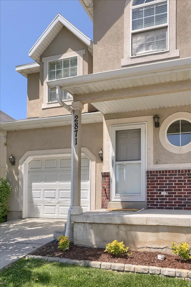 Stucco facade home featuring an attached garage, covered porch entry, and an architectural round window
