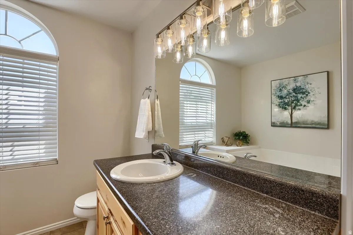 Bathroom featuring a light wood vanity with a built-in sink and dark speckled countertop