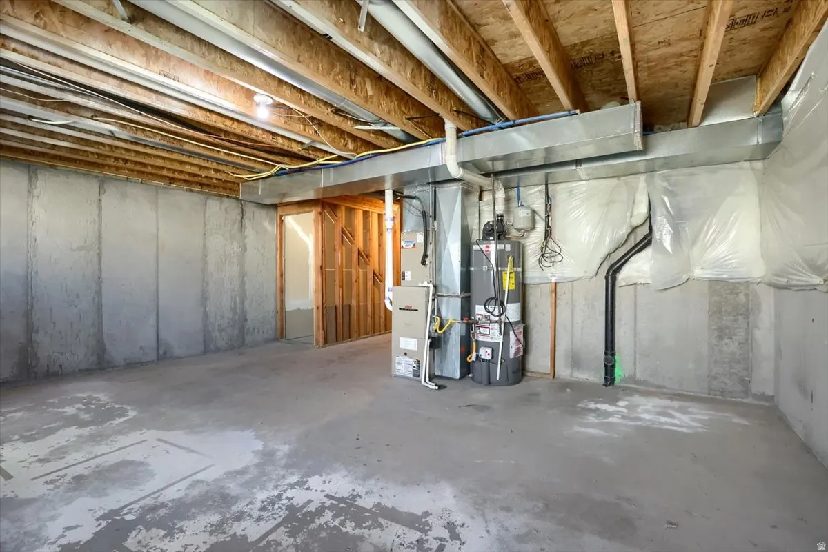 Unfinished basement featuring exposed wood ceiling joists and concrete walls