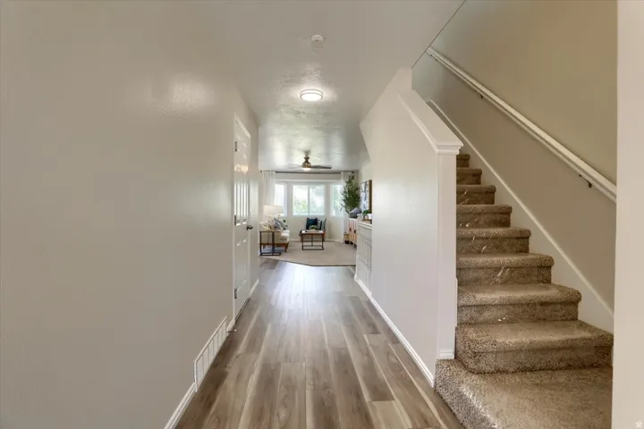 Entryway featuring wood-finish flooring, light neutral paint, a carpeted staircase with white trim, and a white interior door