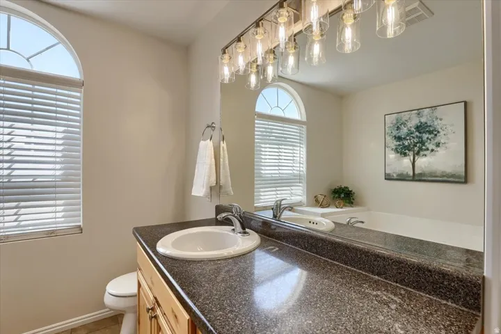 Bathroom featuring a light wood vanity with a built-in sink and dark speckled countertop