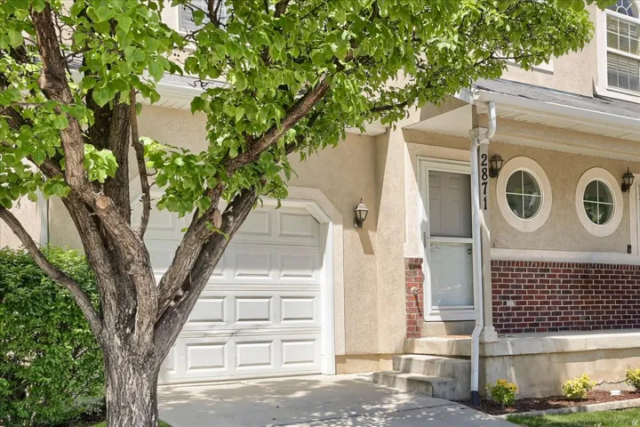 Stucco exterior with brick detailing, white panel garage door, and a front entry with a screen door
