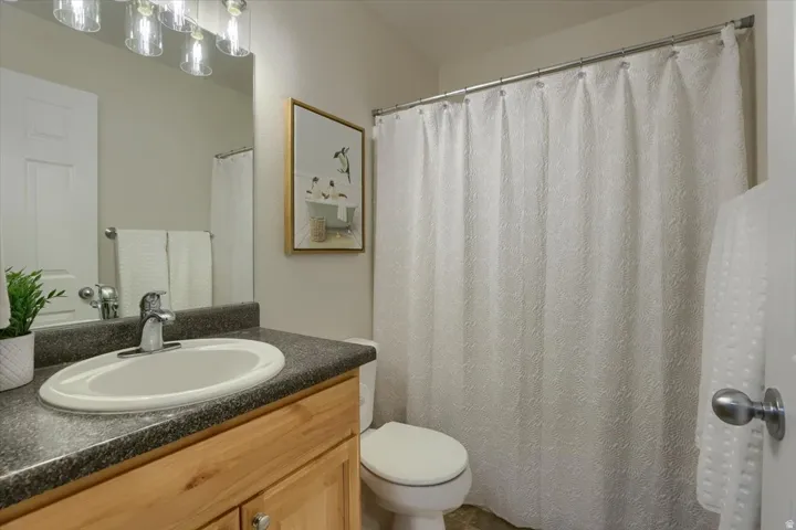 Bathroom featuring a wood-finish vanity with an integrated sink, dark countertop, and brushed nickel fixtures