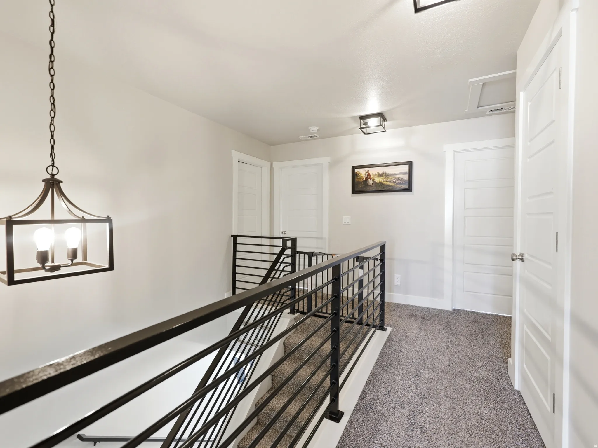 Loft area featuring a contemporary iron chandelier, modern horizontal bar railing, and neutral-toned carpeting