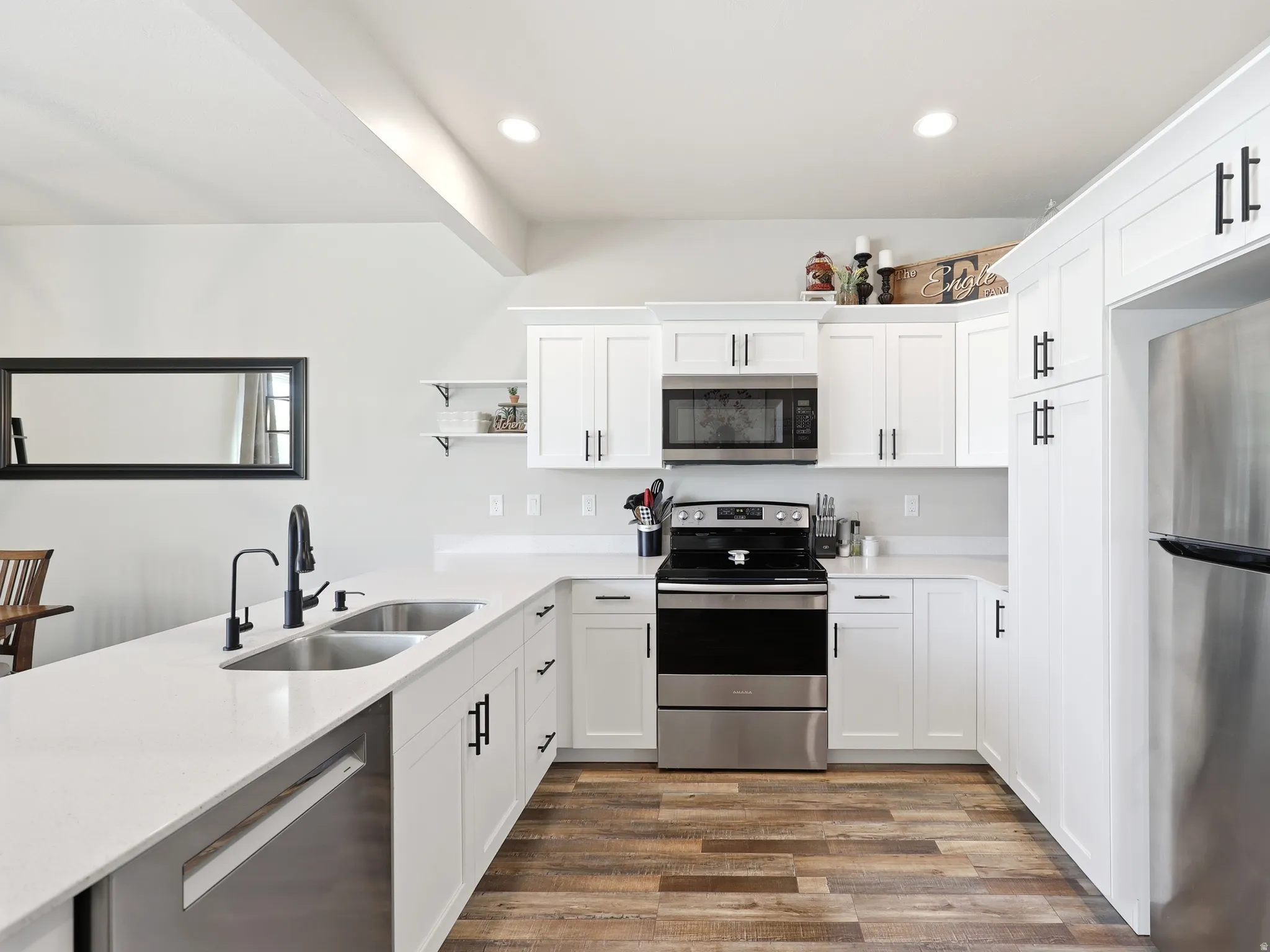 Modern kitchen featuring white shaker cabinetry, stainless steel appliances, and wood-finish flooring
