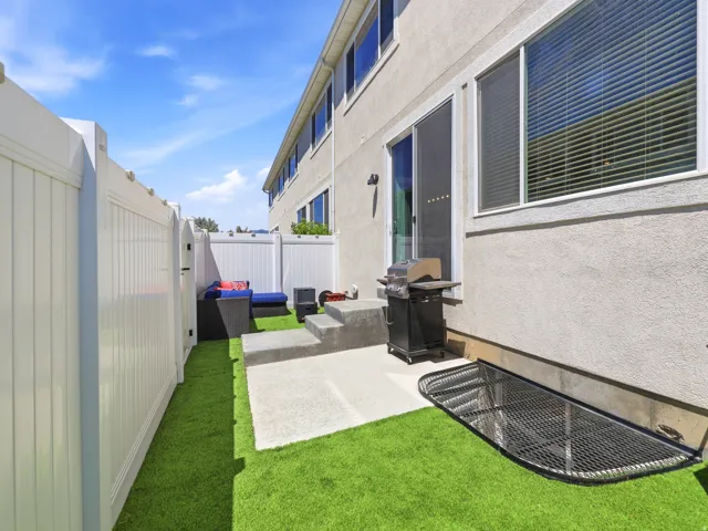 Private outdoor space with an artificial turf lawn and a concrete patio