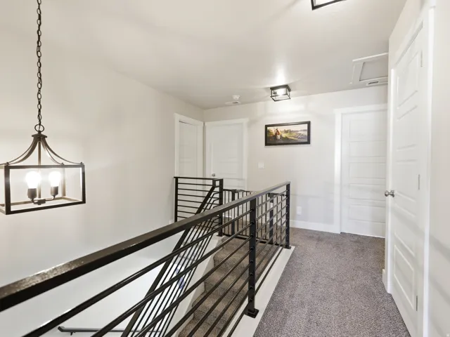 Loft area featuring a contemporary iron chandelier, modern horizontal bar railing, and neutral-toned carpeting