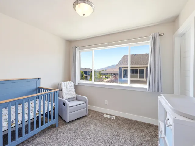 Bright room with a large window, neutral wall paint, and textured carpet flooring