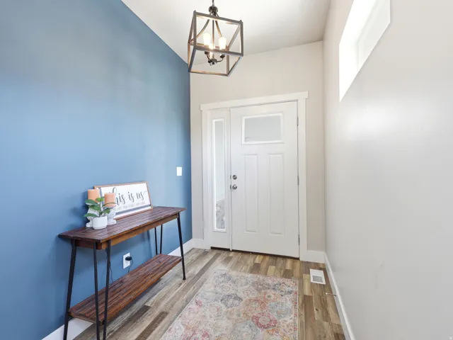 Entryway featuring wood-finish flooring, a white paneled entry door with sidelight and transom window, and a contemporary open-frame chandelier