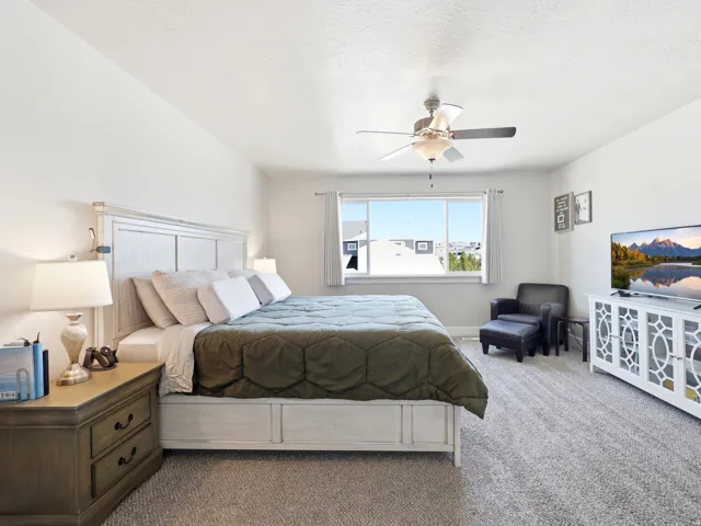 Bedroom featuring light-toned walls, a window with exterior views, and a ceiling fan with integrated lighting