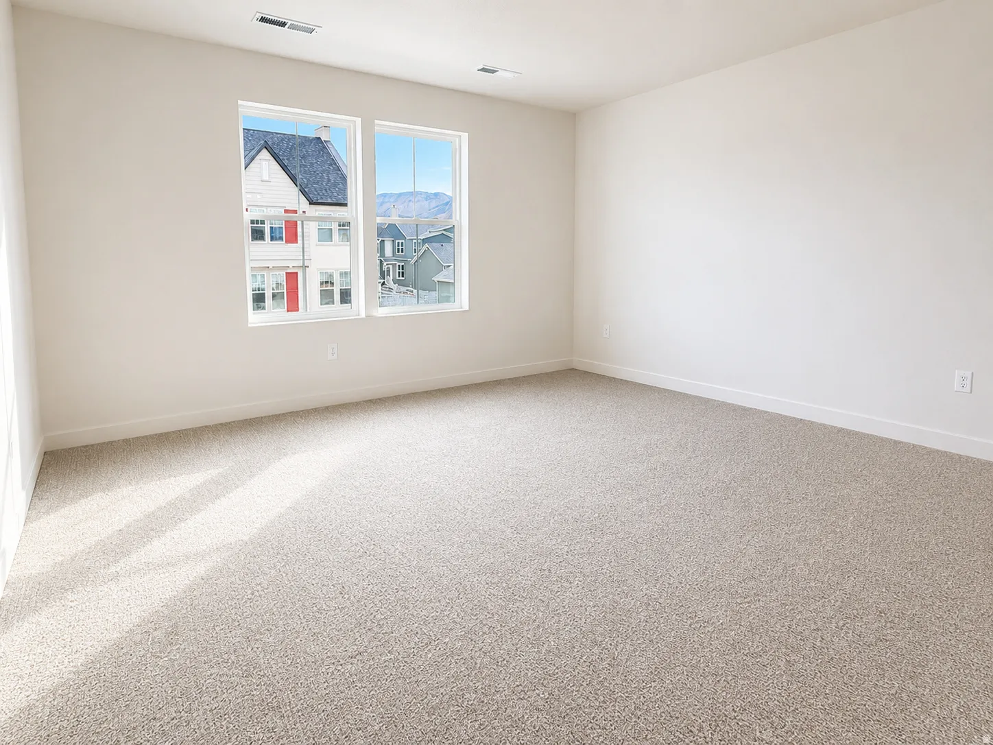 Neutral tone carpeting, dual windows, and white walls
