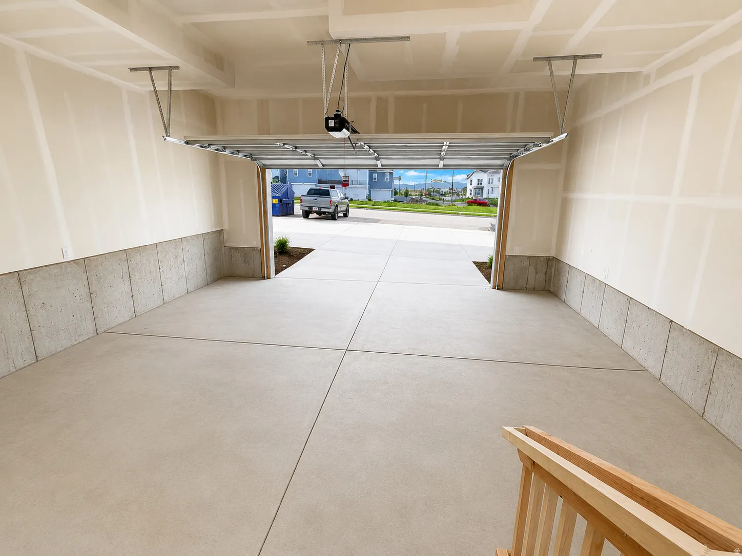 Integrated garage space with a concrete floor, finished walls, and an overhead garage door opener