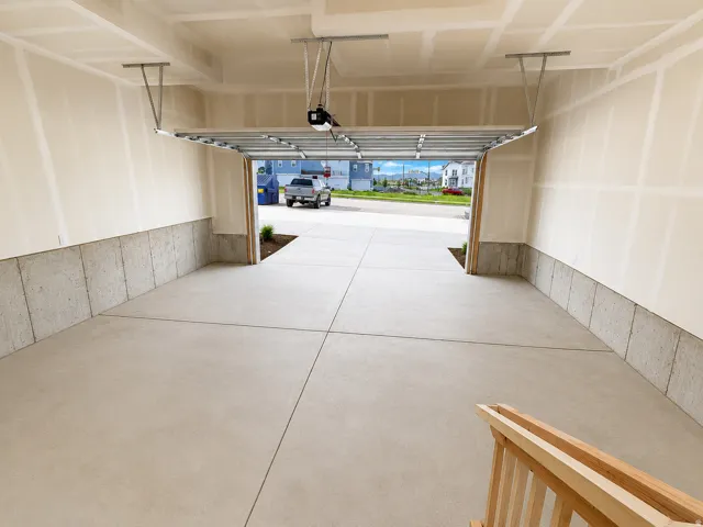 Integrated garage space with a concrete floor, finished walls, and an overhead garage door opener
