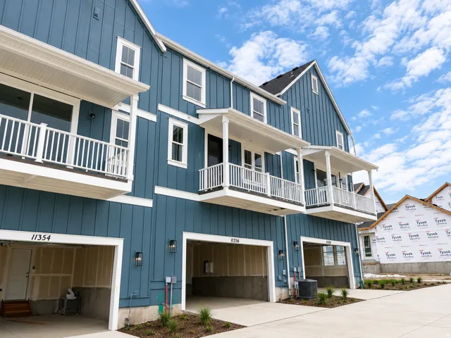 Board and batten siding, white-railed balconies, covered porches, exterior wall lanterns, and integrated single-car garages