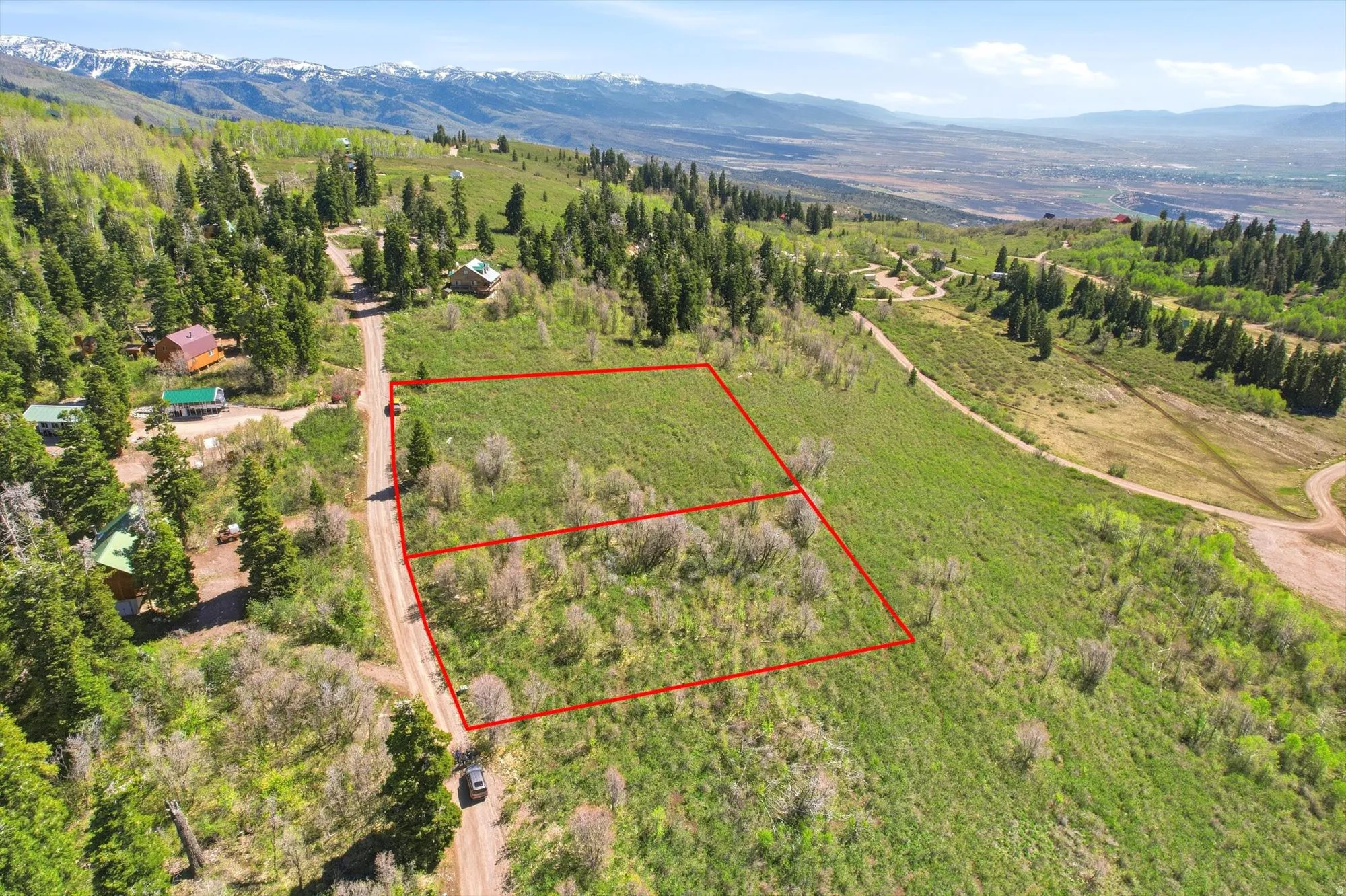 Expansive mountain property featuring an undeveloped terrain with a visible access road