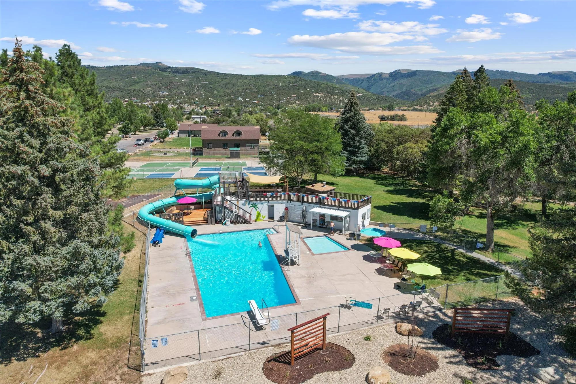 Outdoor swimming pool with a diving board, adjacent water slide, and separate wading pool