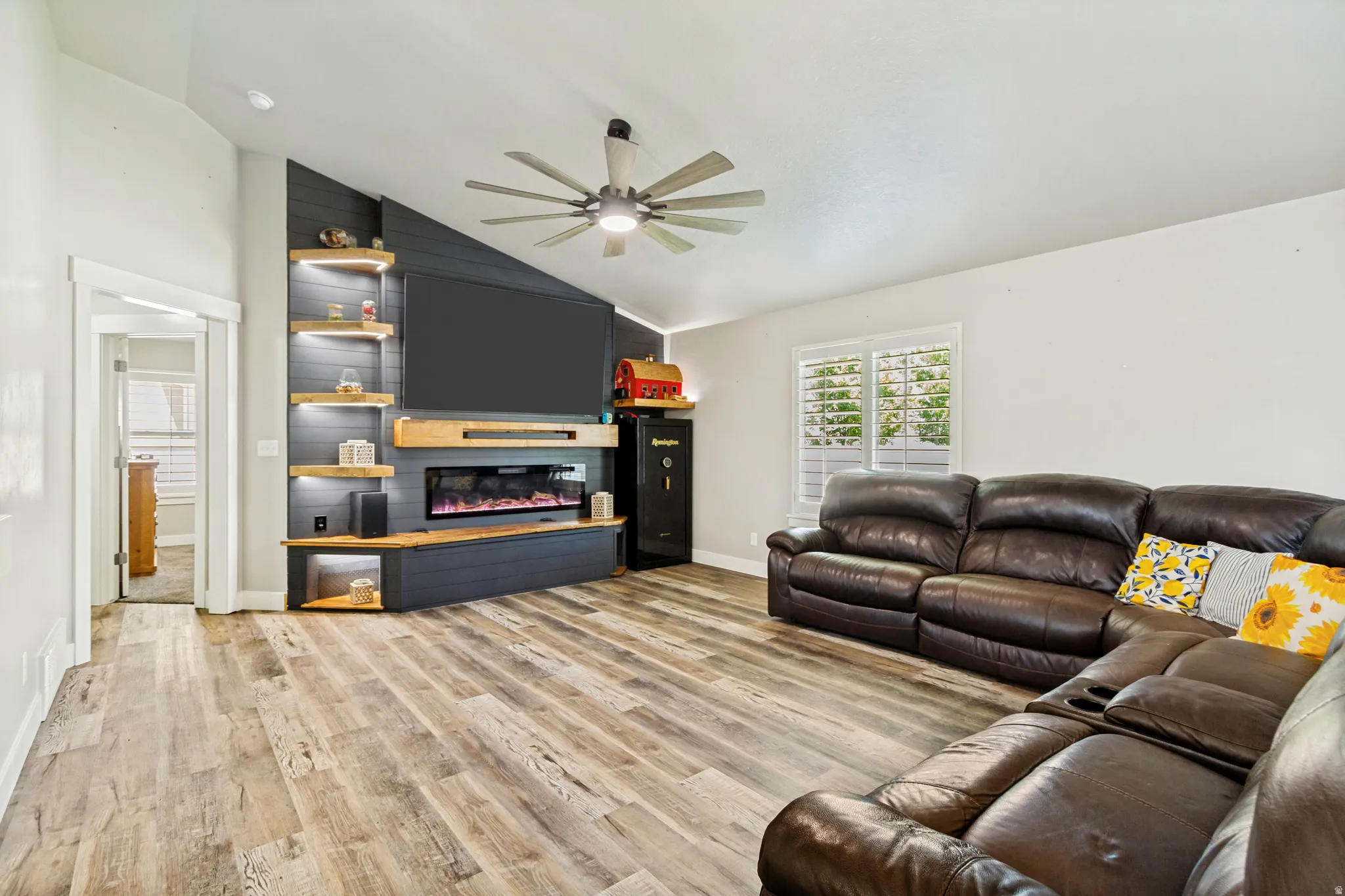 Living area featuring wood-finish flooring and a built-in entertainment center with an electric fireplace, integrated shelving, and accent lighting